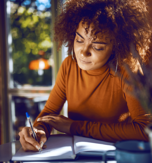 Woman writing in notebook at cafe.