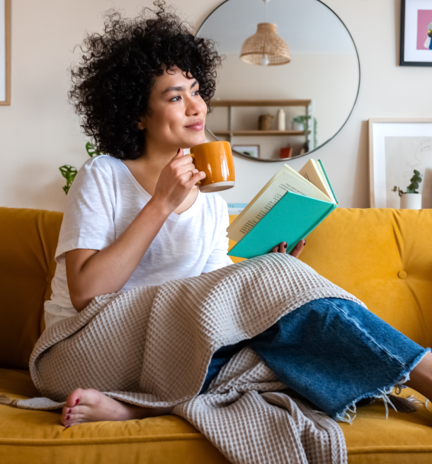 Woman relaxing, reading book, drinking tea.