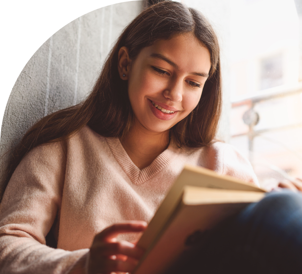 Girl smiling while reading a book.