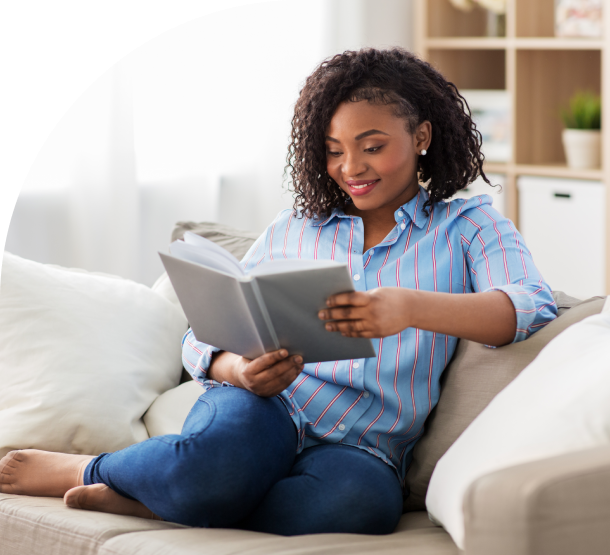 Woman relaxing, reading a book on couch.